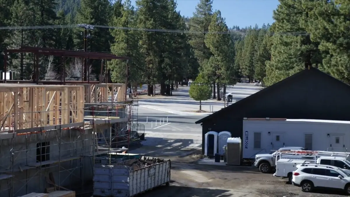 Construction framing beside trees and service vehicles for Rebuild Plumbing After the Eaton Fire: What Altadena Homeowners Should Know